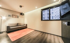 Una sala de estar moderna con un sofá, una mesa de centro, una lámpara de pie y una ventana con vistas a edificios.