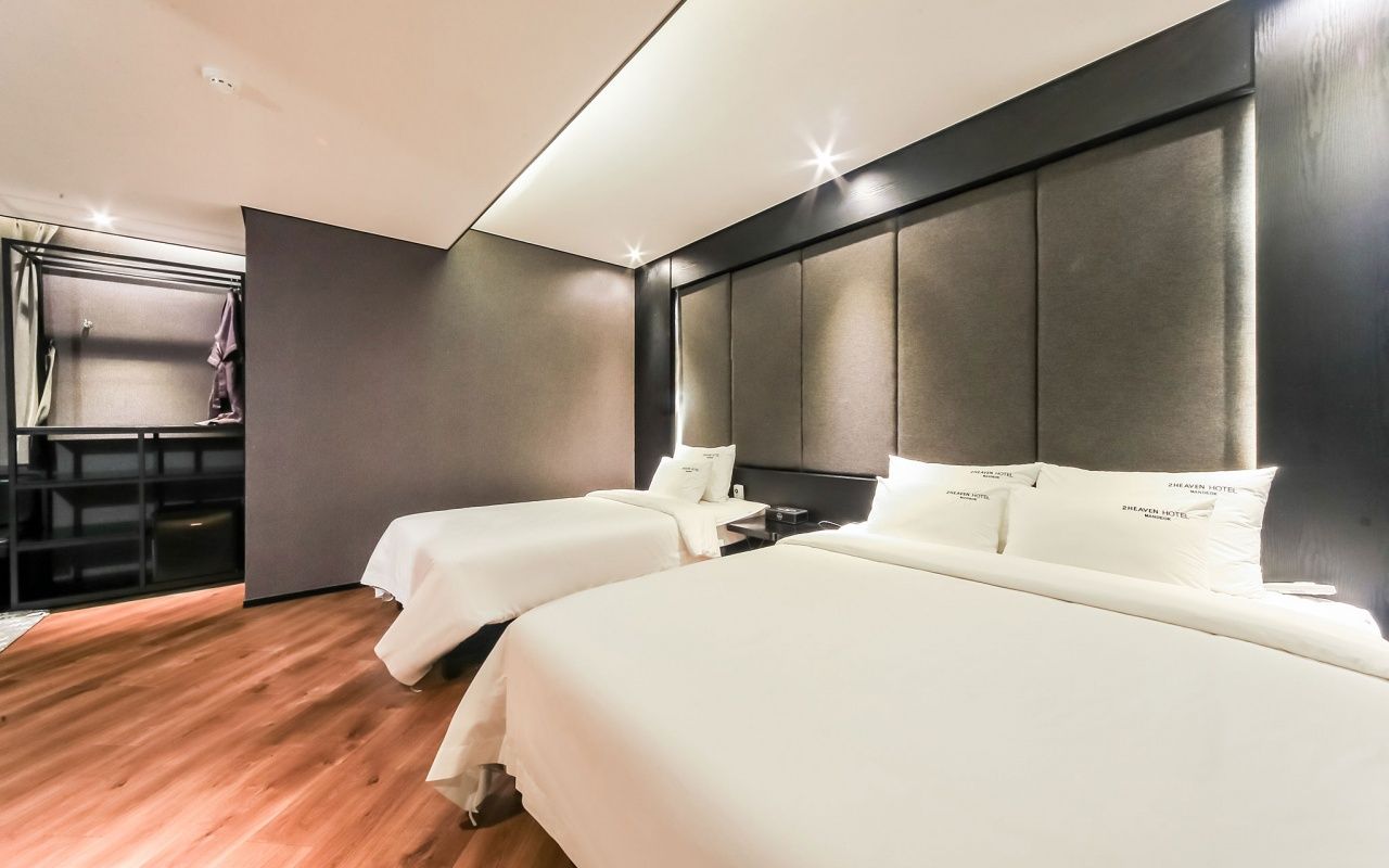 Habitación de hotel con dos camas, un escritorio y zona de ducha.