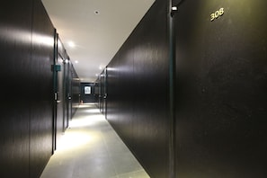 Un pasillo con puertas a ambos lados, piso de baldosas y el número '308' en la pared derecha.