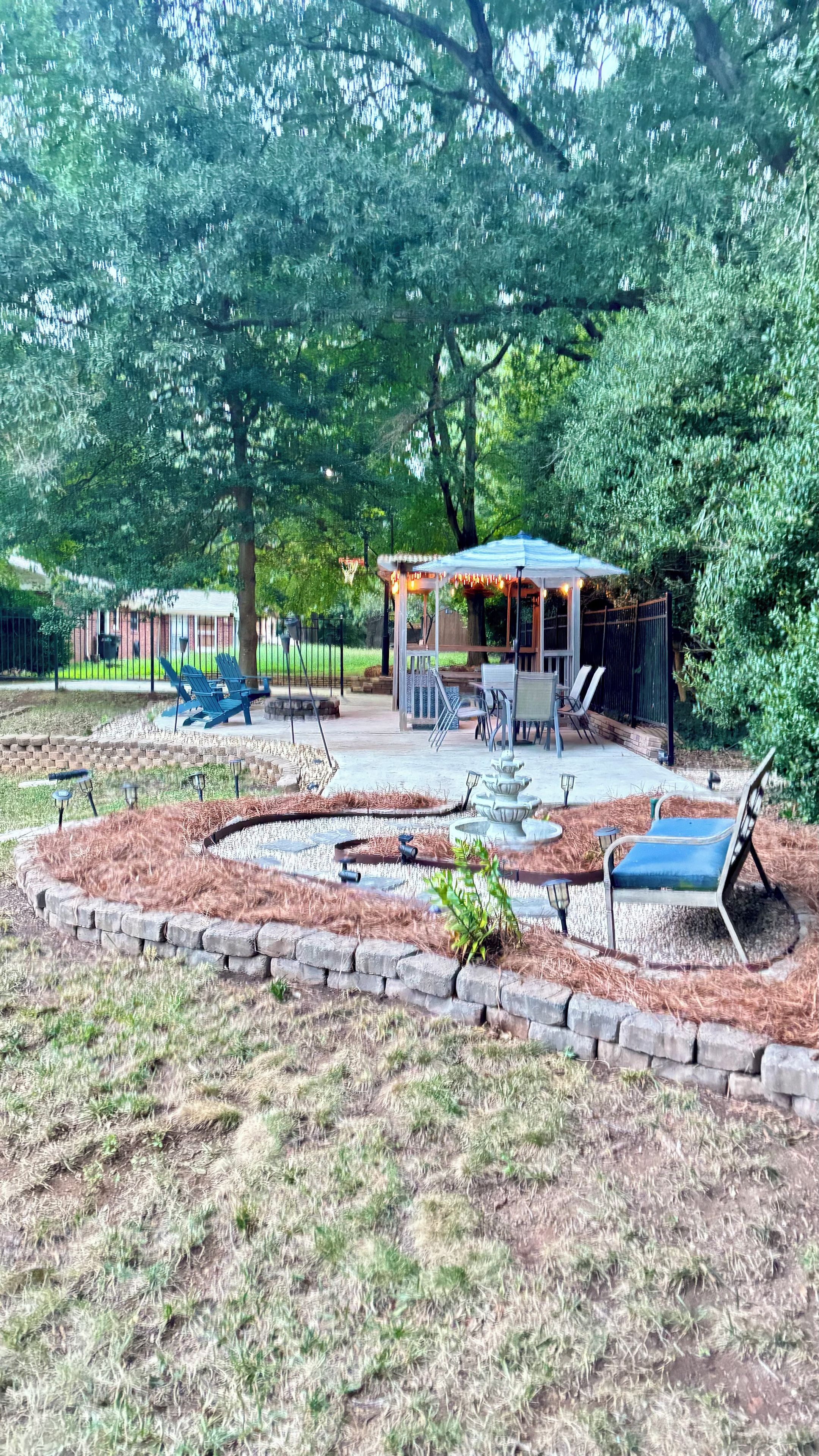 Eine Terrassenanlage mit Sitzgelegenheiten im Freien, einer Pergola und einem kleinen Wasserspiel.