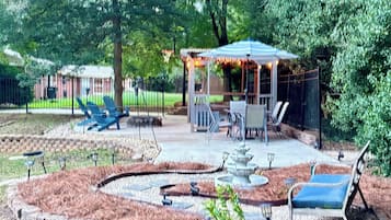 Eine Terrassenanlage mit Sitzgelegenheiten im Freien, einer Pergola und einem kleinen Wasserspiel.