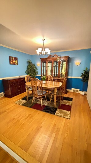 A dining room with a wooden table and chairs, a chandelier, and a blue wall. - Family-Friendly 3BR with Private B-Ball Court & Patio (Statesville)