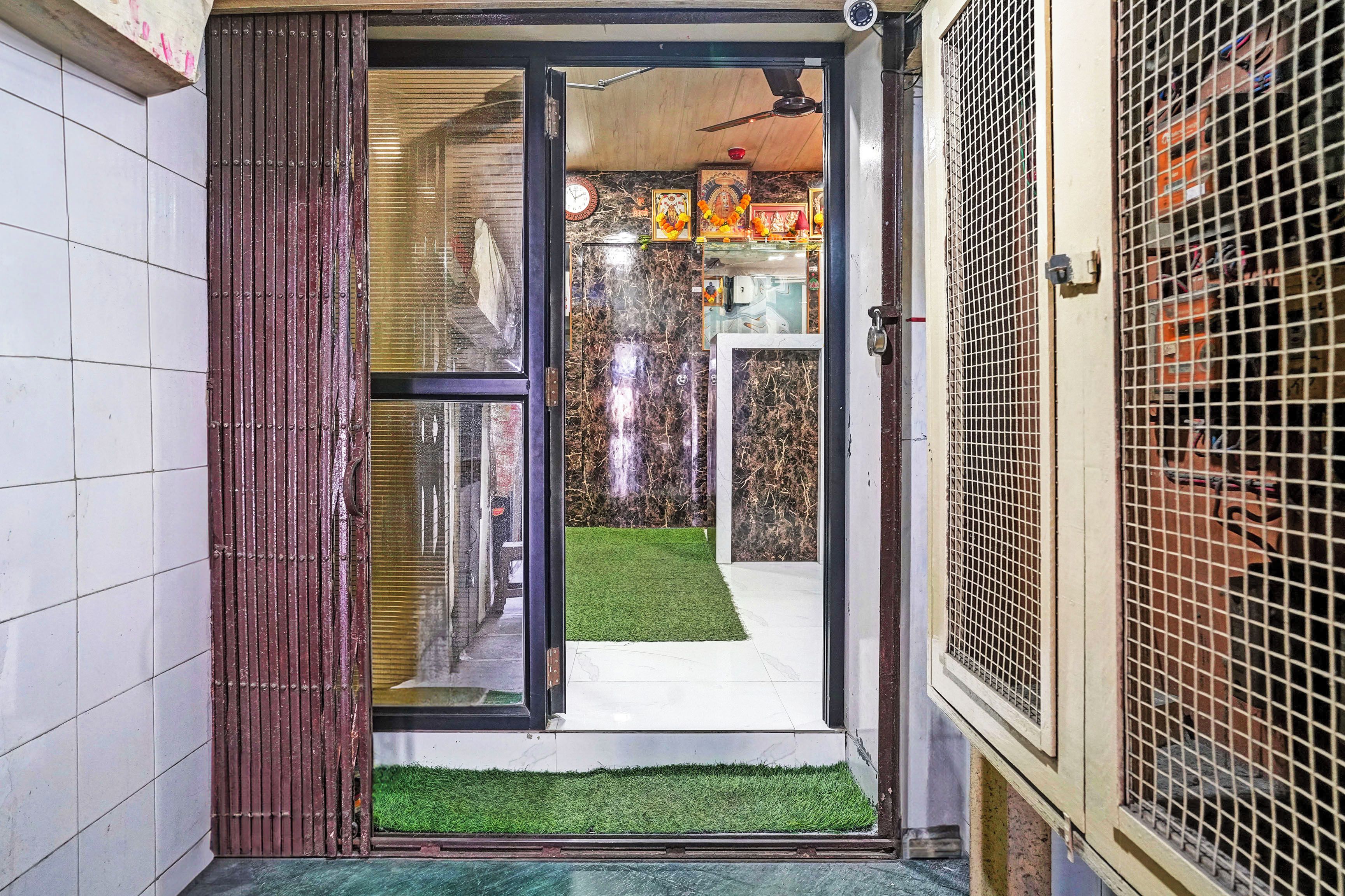 A doorway leading to a room with a small artificial grass area, a clock, and a framed picture on the wall.