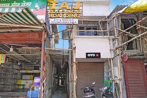 Un callejón estrecho con un letrero de Taj Lodging & Boarding que ofrece habitaciones con aire acondicionado y sin aire acondicionado.