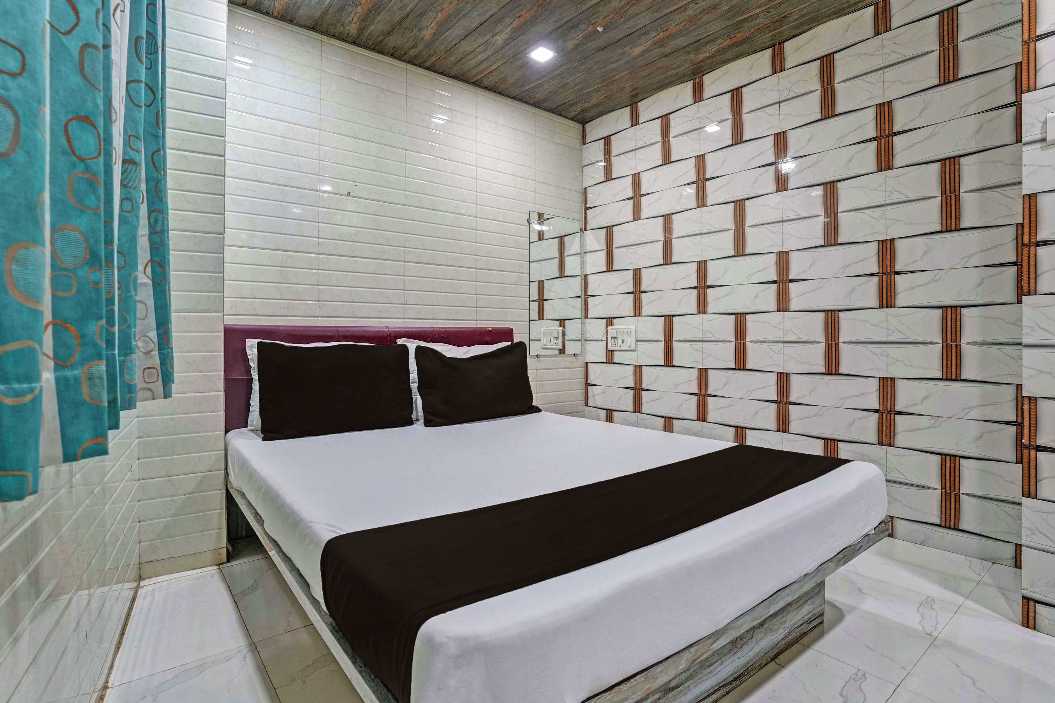 A hotel room with a bed, a headboard, and a wall with a patterned design.
