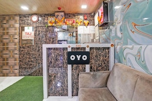 Una zona de recepción con un letrero de salida, un reloj y un cartel con la marca 'OYO'.
