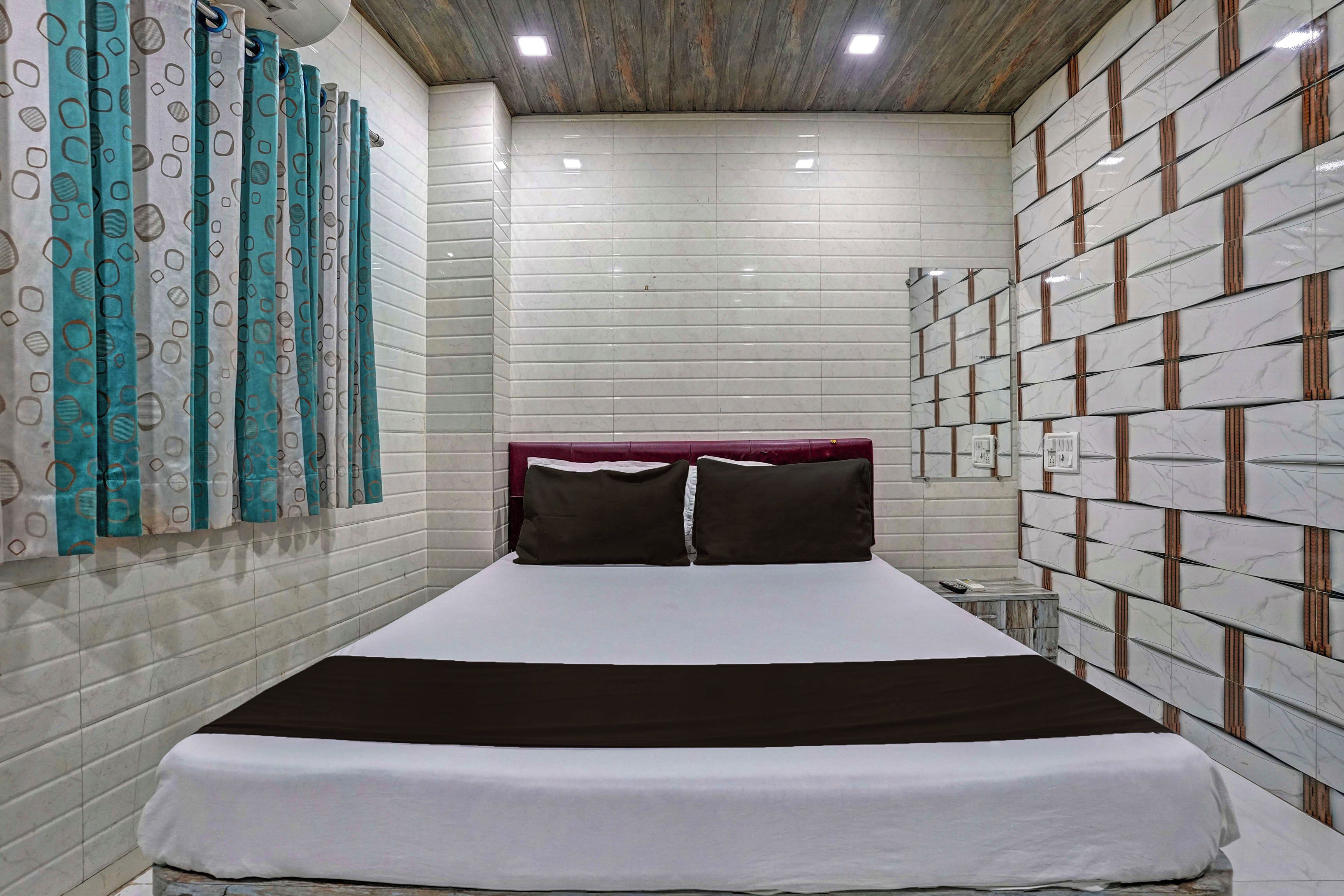A hotel room with a bed, curtains, and a tiled wall.