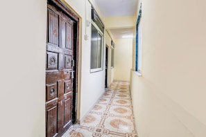 Un pasillo estrecho con una puerta de madera y baldosas de suelo con diseños.