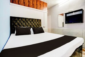 A hotel room with a large bed, a wooden headboard, a flat-screen TV mounted on the wall, and marble-patterned walls. - Hotel O Vira Palace (Mumbai)