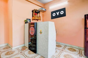 A room with a refrigerator, a wall-mounted sign reading 'OYO', and a decorative item on top of the refrigerator.