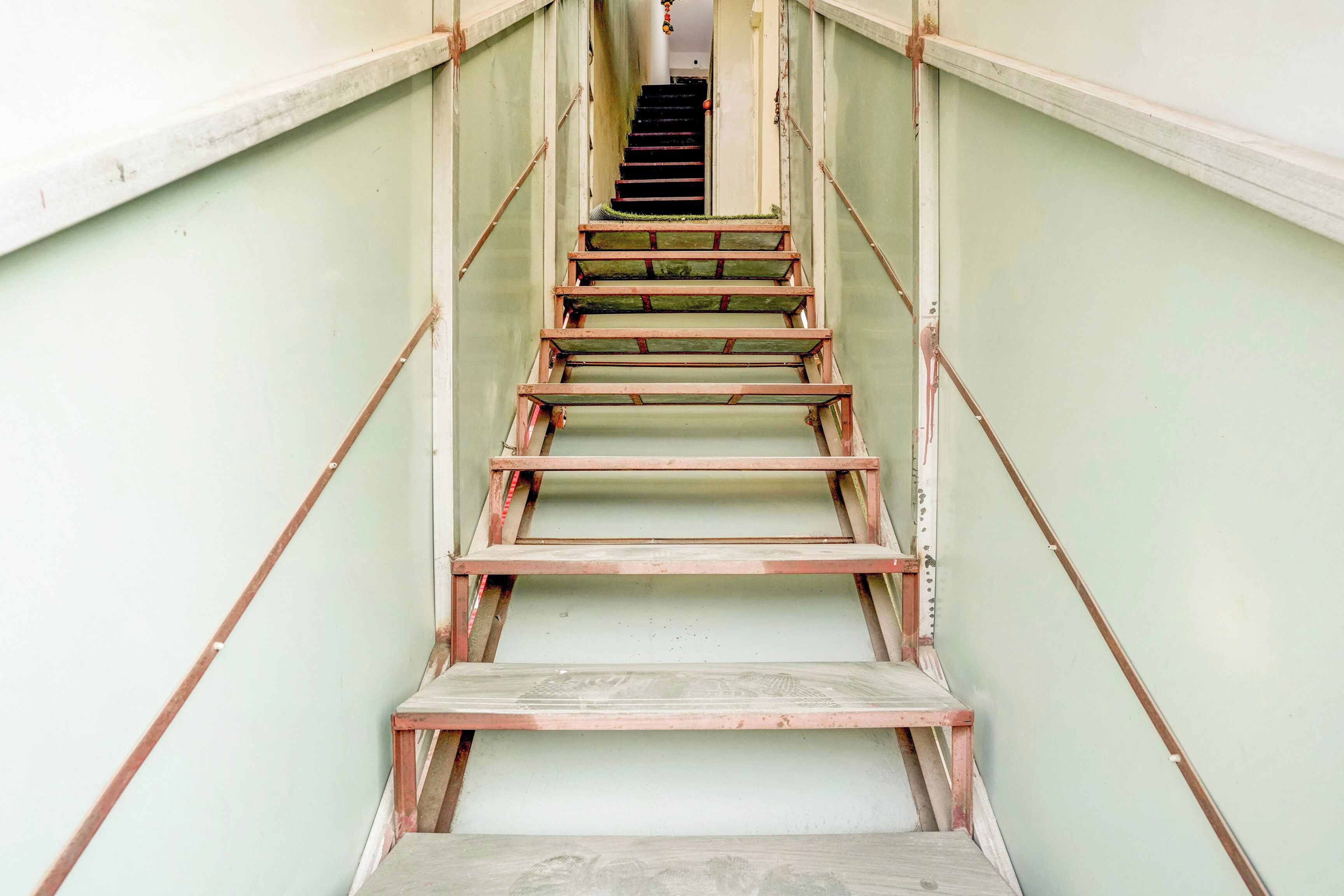 Una escalera con barandas metálicas y peldaños de madera que lleva a una puerta en la parte superior.