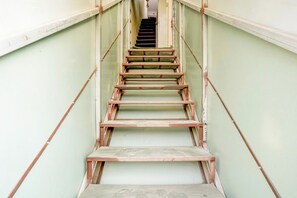 Una escalera con barandas metálicas y peldaños de madera que lleva a una puerta en la parte superior.