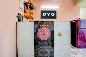 Una habitación con un equipo de aire acondicionado instalado en la pared, un mueble de madera con un objeto decorativo y un letrero con la palabra 'OYO'.