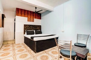 A bedroom with a bed, a chair, a small table, and a ceiling fan.