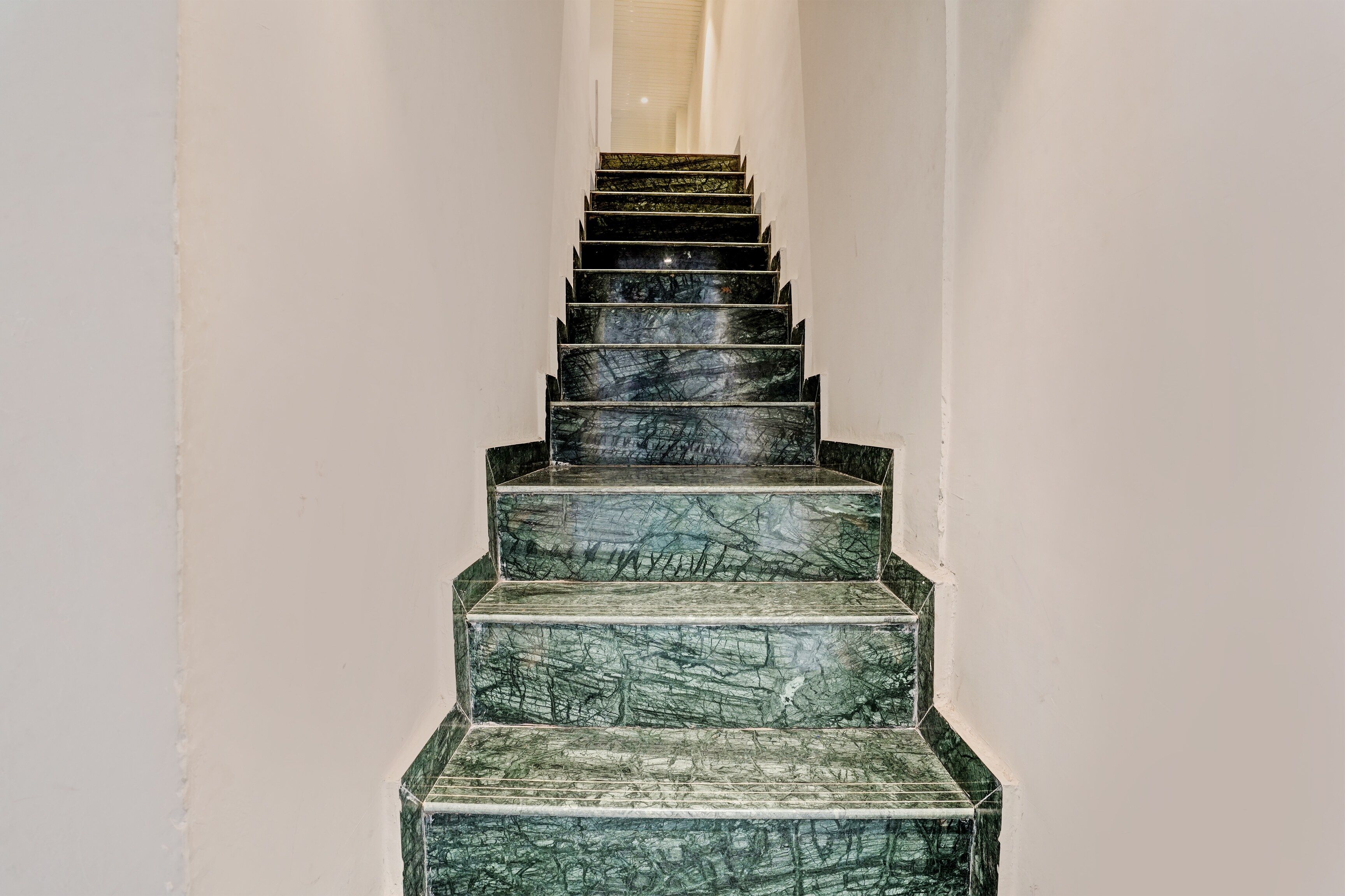 Una escalera con acabado de mármol que sube a un piso superior.
