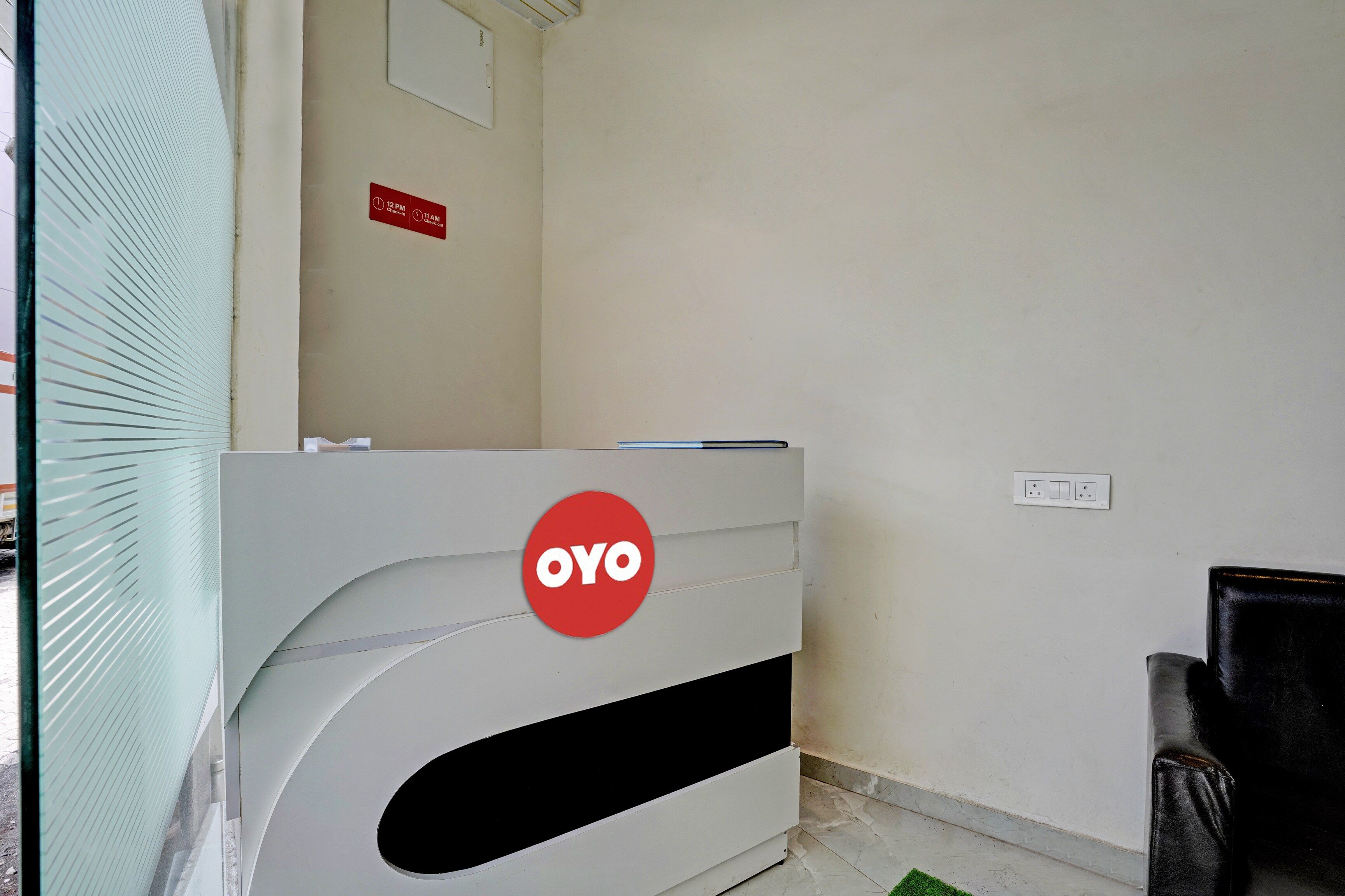 Una reception con il logo 'OYO', un segnale per il check-in e una presa a muro.