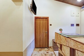 A hallway with a wooden door marked '107', a small plant on a counter, and a marble-patterned floor.