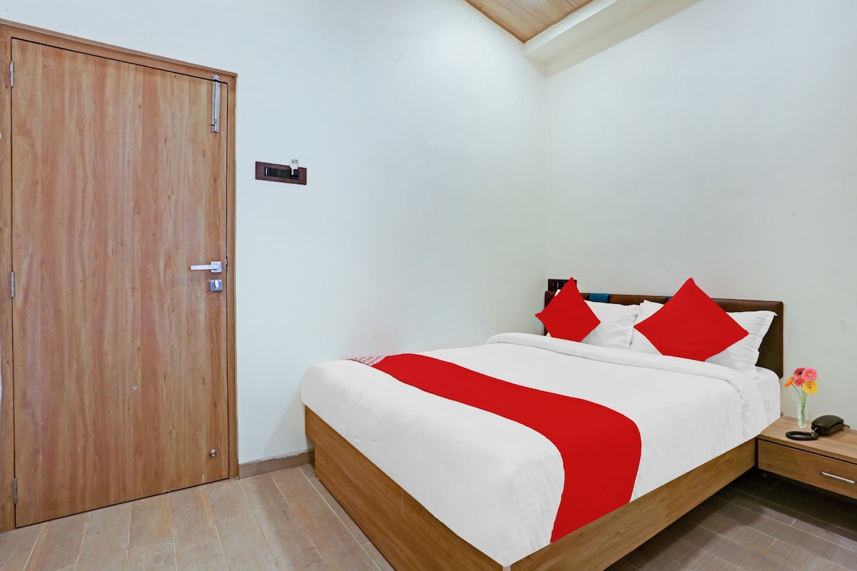 A hotel room with a wooden bed, a nightstand, a bedside table, and a wooden wardrobe.