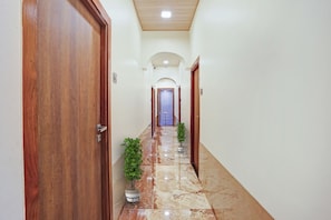 A hallway with wooden doors, a marble floor, and potted plants.