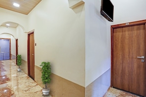 A hallway with a marble floor, wooden doors, and potted plants.