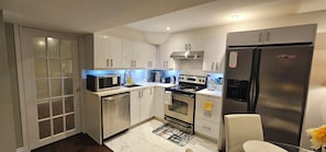 Een moderne keuken met roestvrijstalen apparatuur, witte kastjes en een marmeren achterwand.