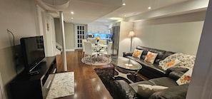 Een moderne woonkamer met een glazen salontafel, een leren bank en een flatscreen televisie.
