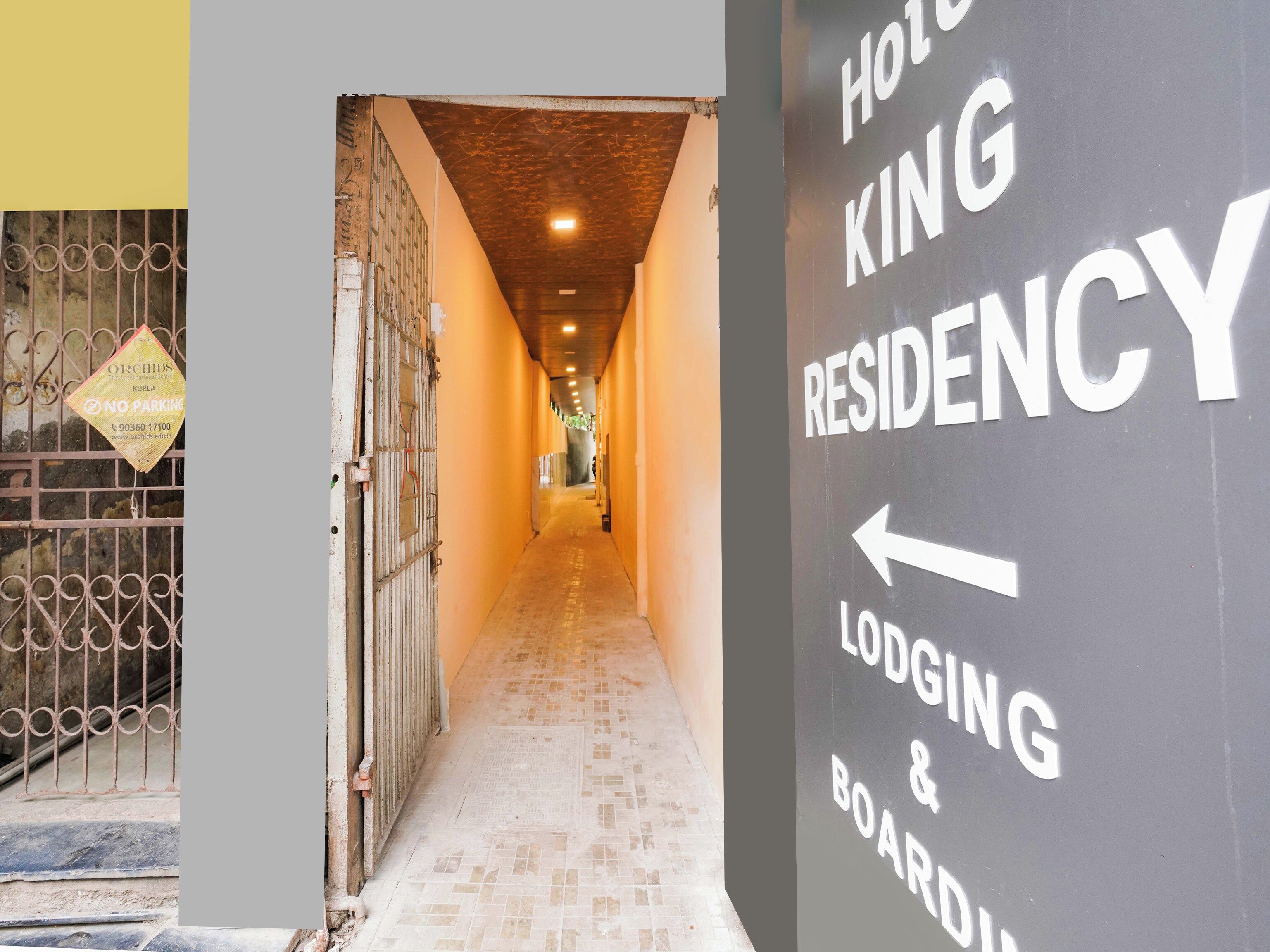 Un passadís que condueix a un hotel, amb un senyal que indica 'HOTEL KING RESIDENCY LODGING & BOARDING'.