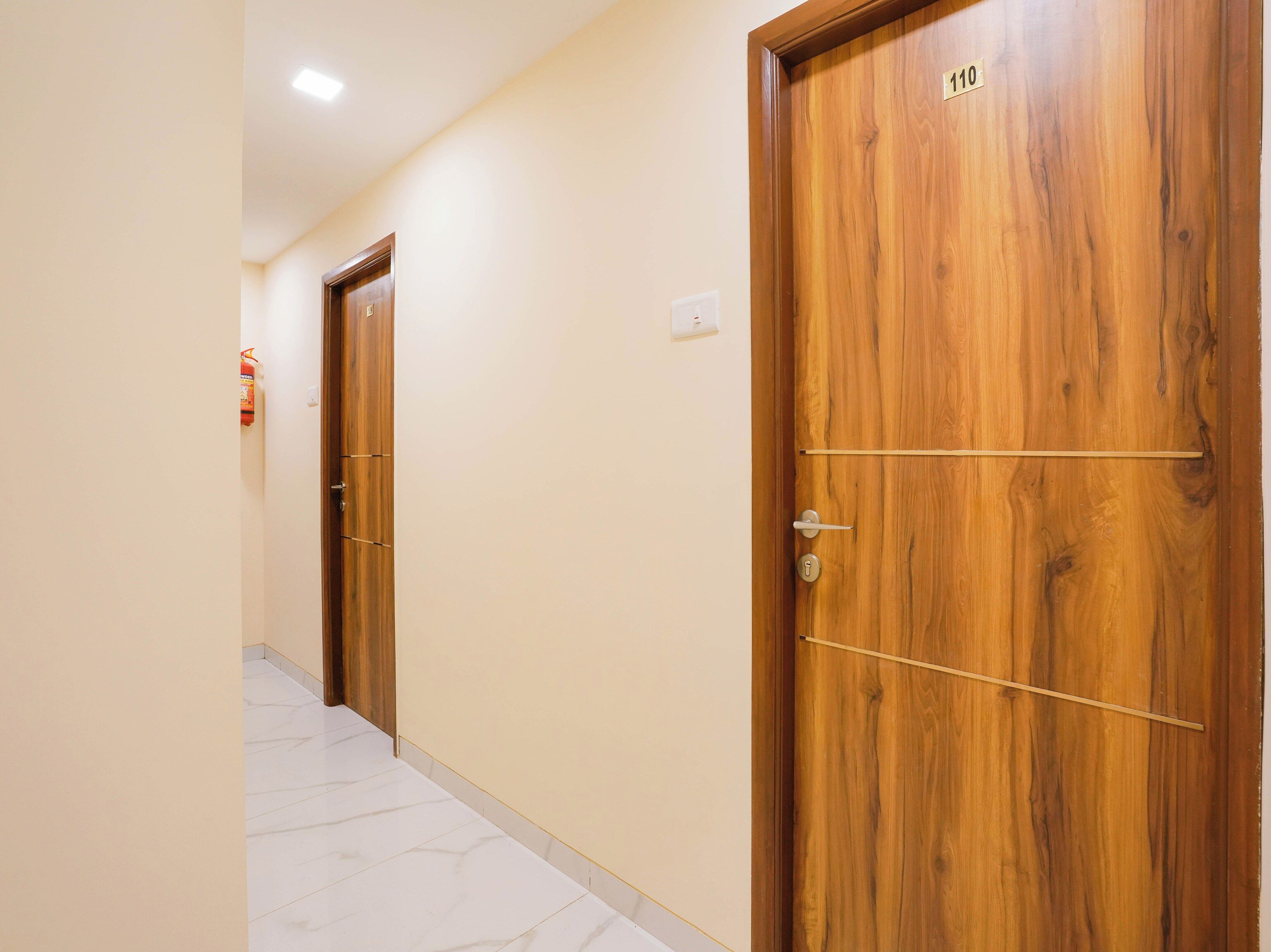 Un pasillo con dos puertas de madera, una de ellas con el número 110 a la vista.