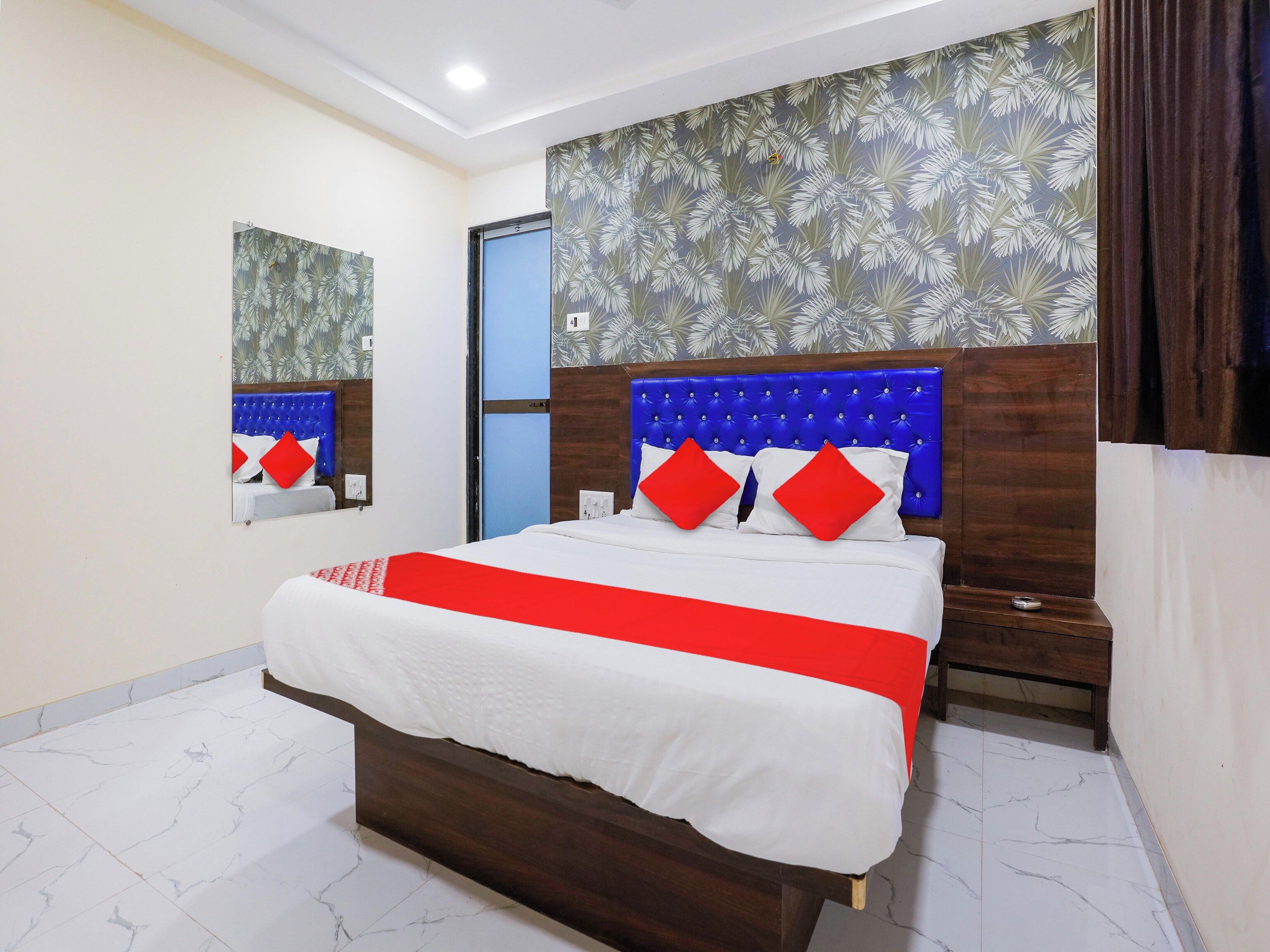 Una habitación de hotel con una cama grande, un cabecero de madera, un espejo y una puerta.
