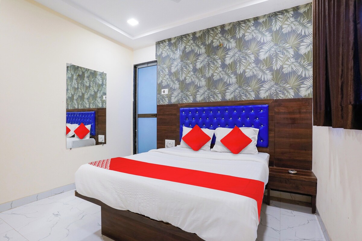 Una habitación de hotel con una cama grande, un cabecero de madera, un espejo y una puerta.