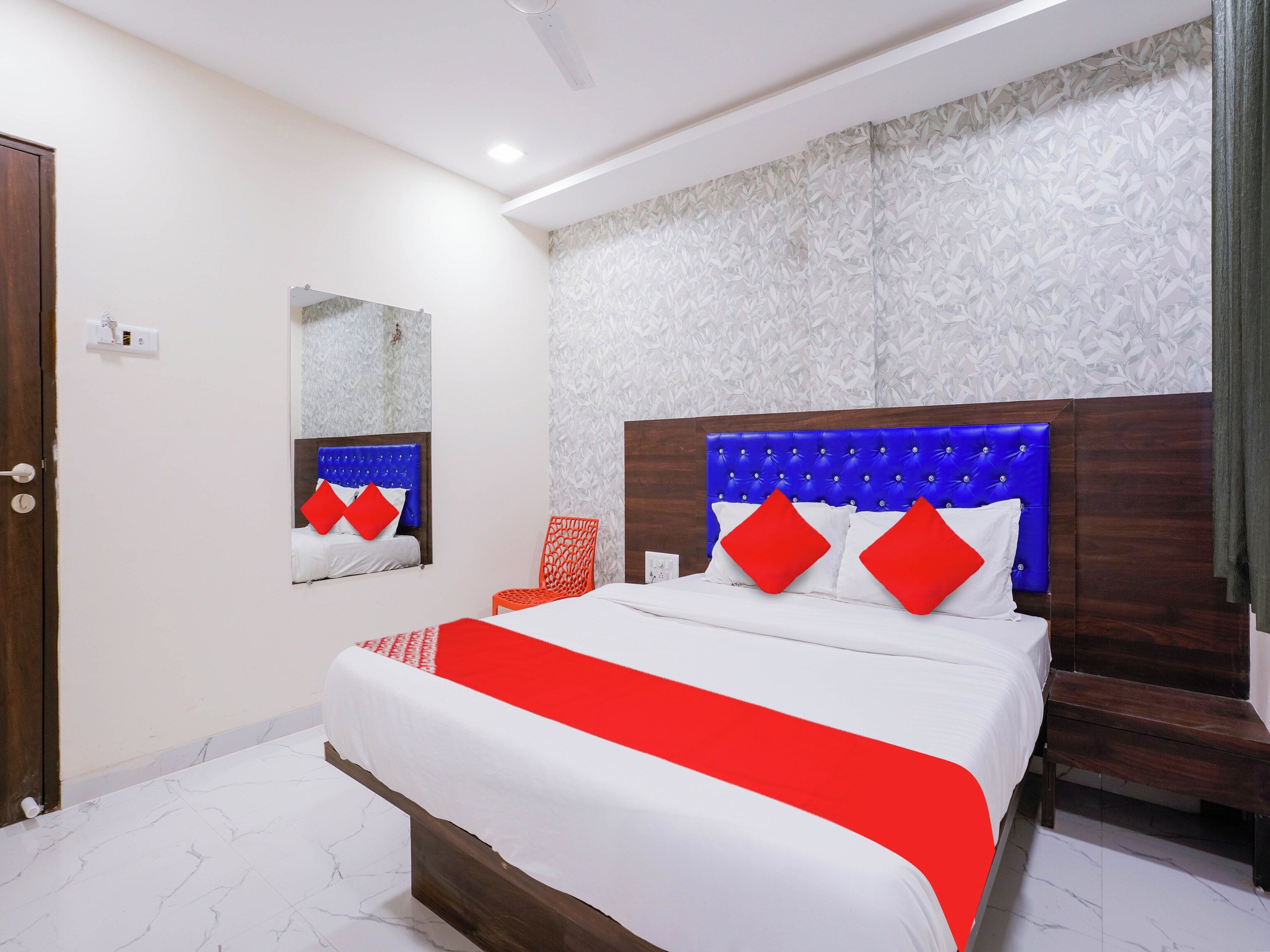 A hotel room with a large bed, a wooden headboard, and a patterned wall.