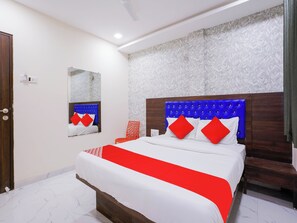 Een hotelkamer met een groot bed, een houten hoofdeinde en een kamer met een patroon op de muur.