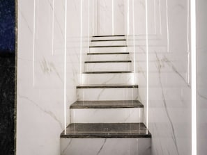 Un conjunto de escaleras de mármol con barandilla de vidrio.