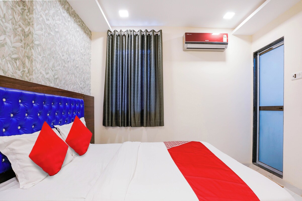Een hotelkamer met een bed, hoofdeinde, raam met gordijnen, een airconditioning en een deur.