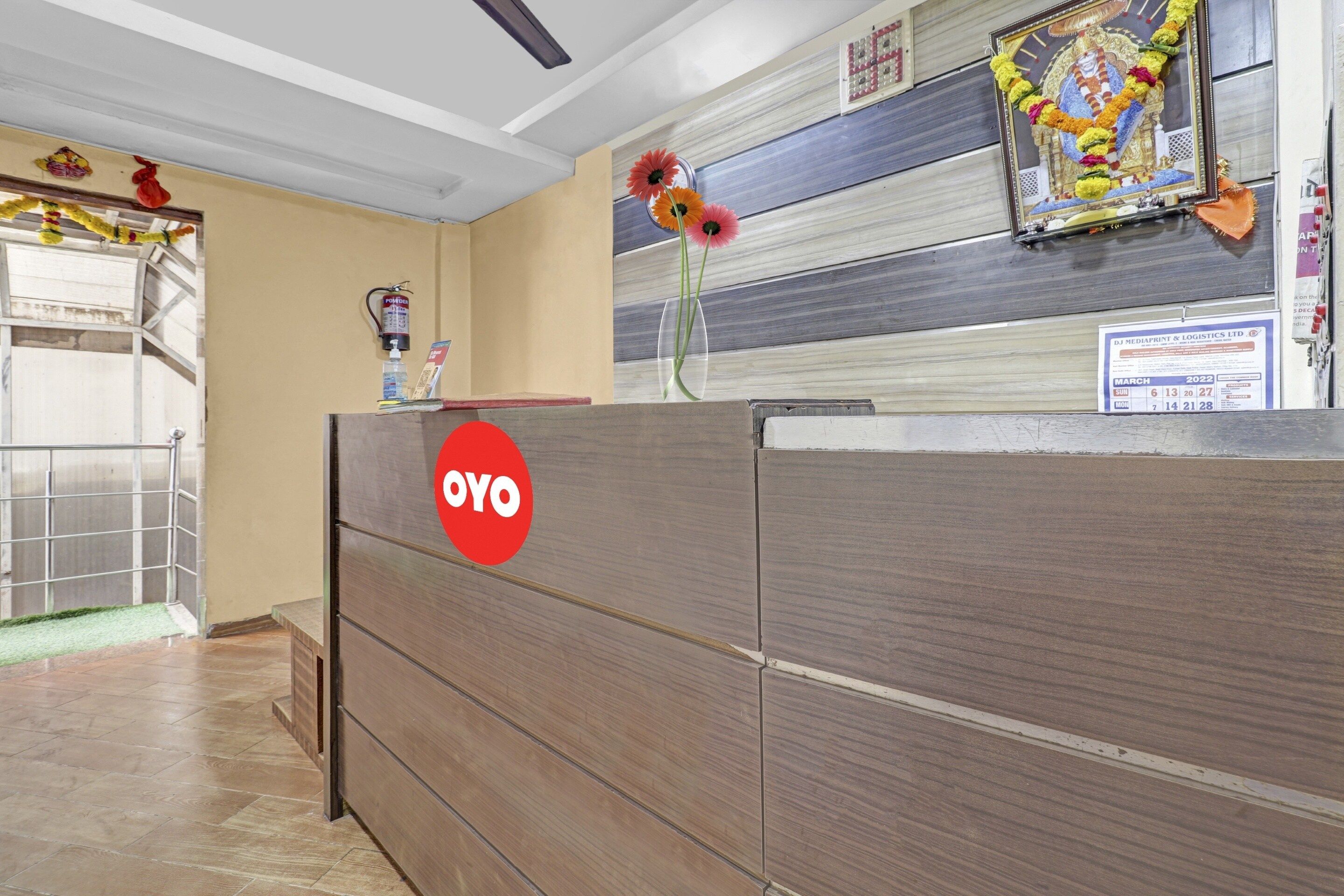 A reception desk with a red logo, a wall-mounted calendar, and a decorative garland.