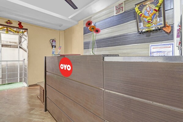 Un comptoir d’accueil avec un logo rouge, un calendrier fixé au mur et une guirlande décorative.