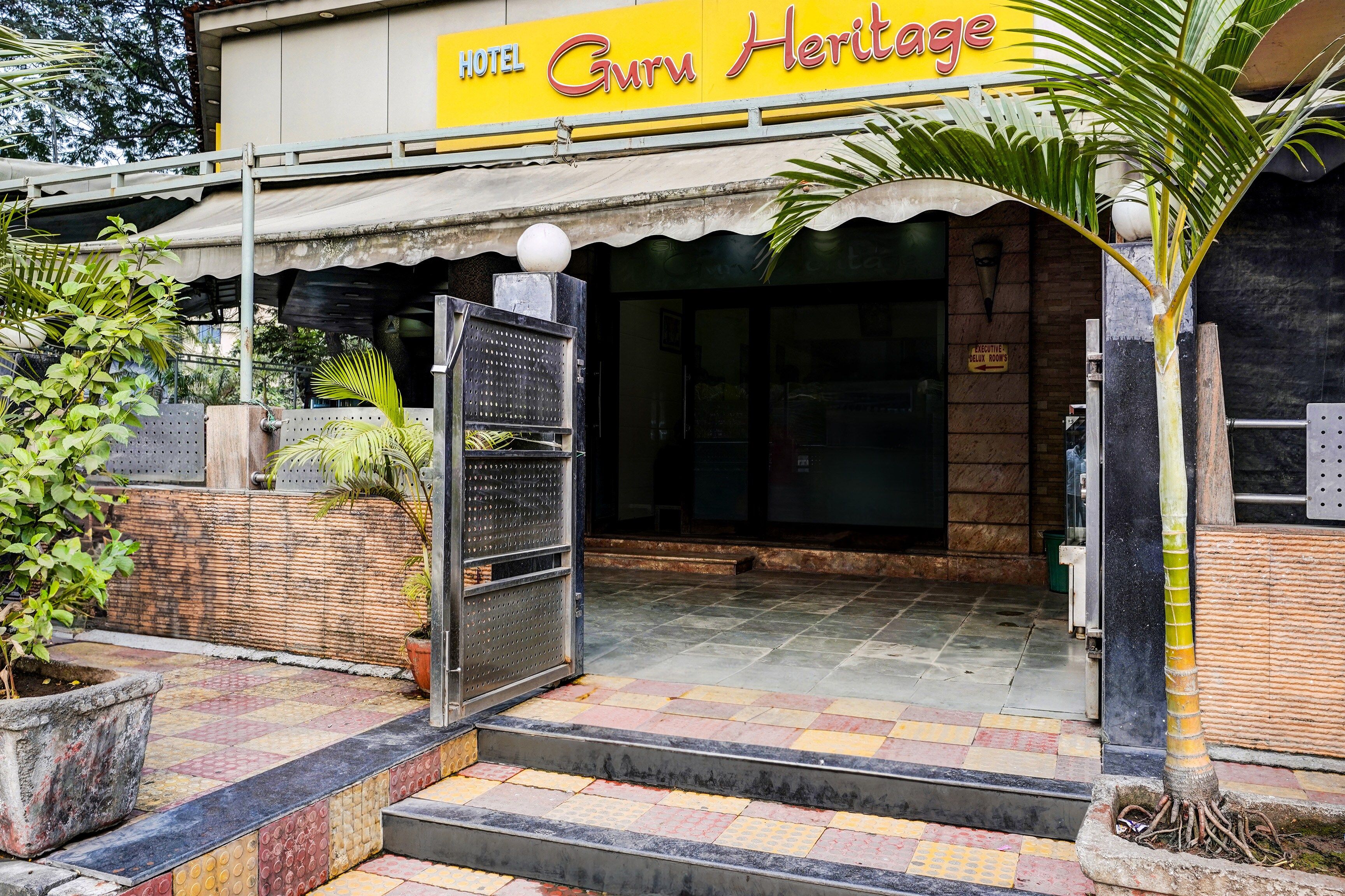 Entrada de hotel con un cartel que dice 'Hotel Guruv Heritage'.