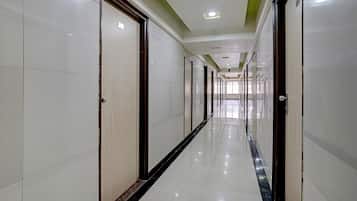 Un largo y estrecho pasillo de hotel con puertas a ambos lados, suelo de baldosas e iluminación empotrada.