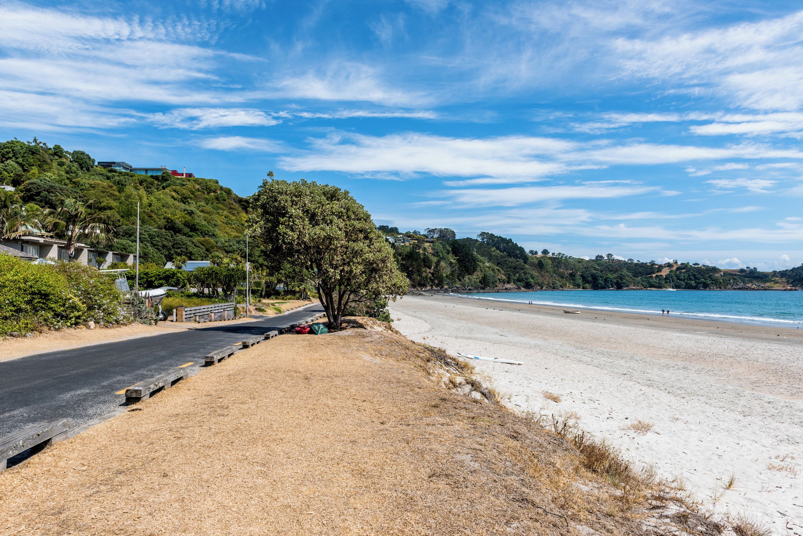 A coastal road leading to a sandy beach with a clear sky.
