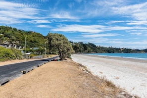 A coastal road leading to a sandy beach with a clear sky.