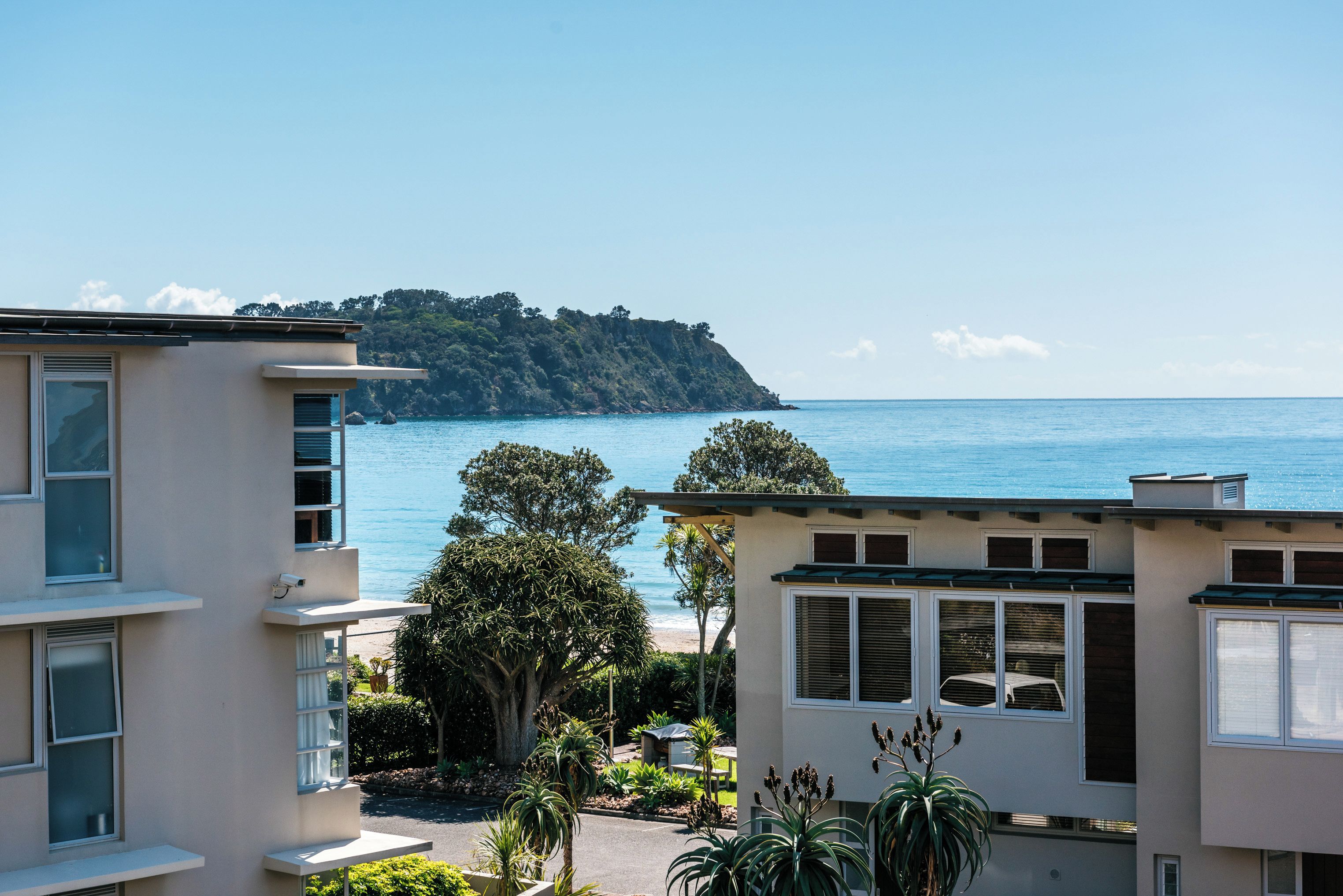 Una zona residencial costera con edificios que dan al mar, con balcones y vistas a una colina distante.