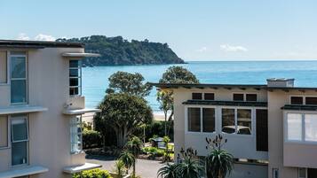 Una zona residencial costera con edificios que dan al mar, con balcones y vistas a una colina distante.