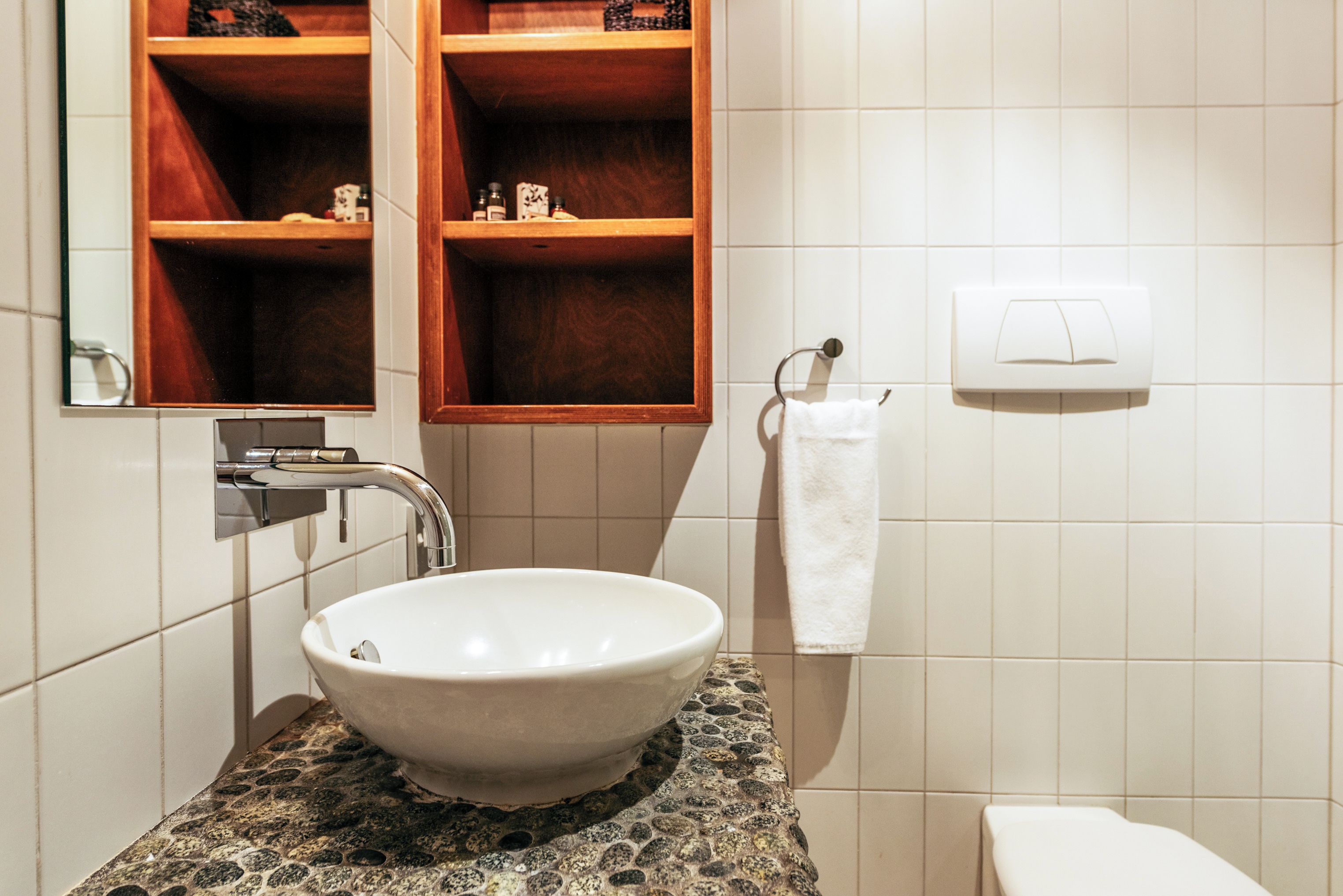 Ein Badezimmer mit einem weißen Waschbecken, einem Spiegel und einem Handtuchhalter.