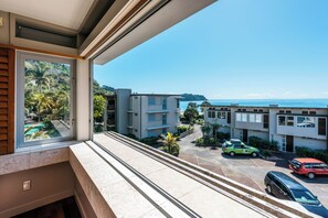 A residential building with a view of the ocean and parked cars.