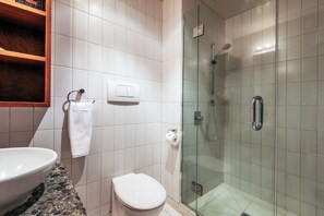 A bathroom with a toilet, a sink, a glass-enclosed shower, and a towel rack. - Sanctuary On The Beach (Waiheke Island)