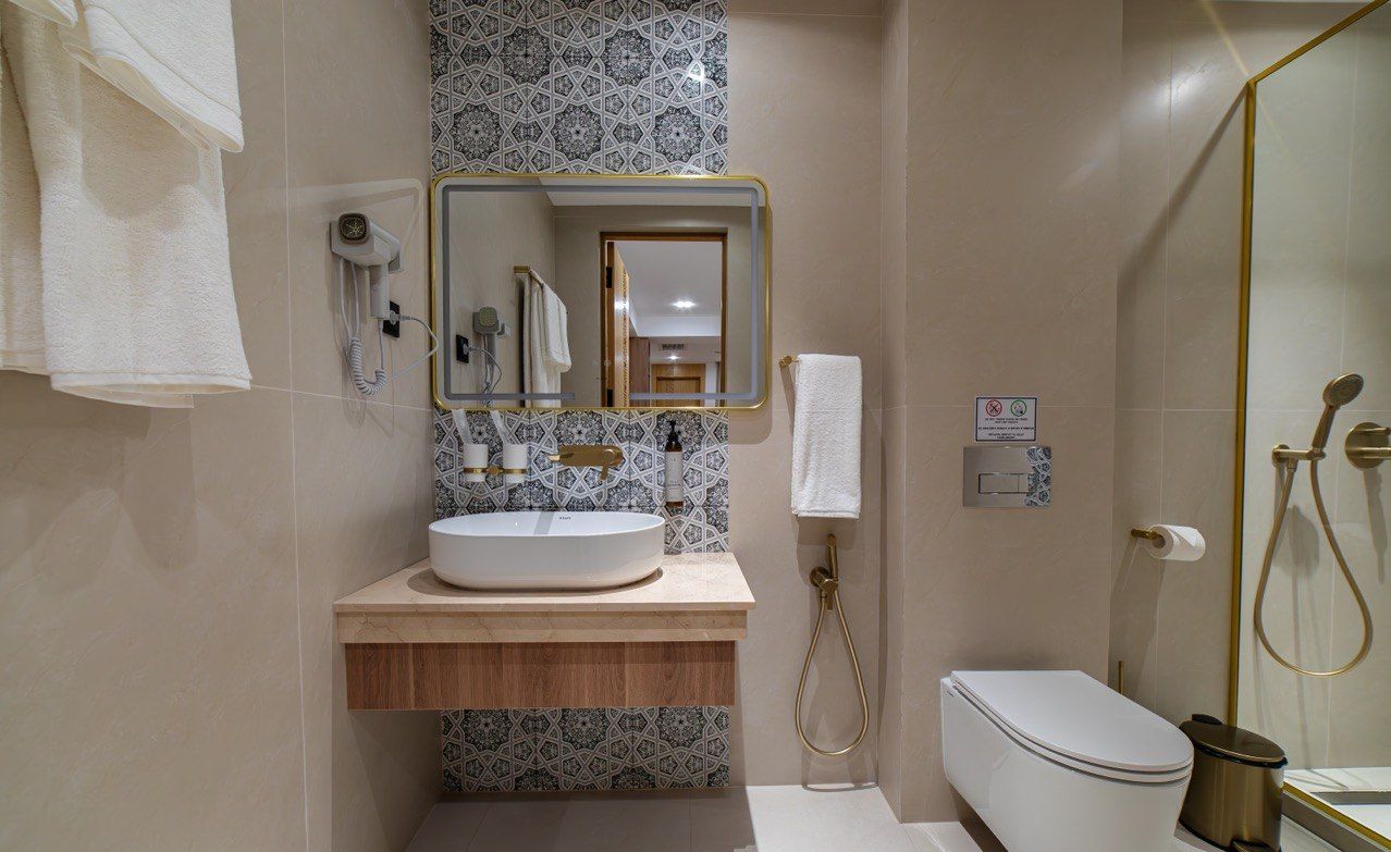 Un baño con lavamanos blanco, un espejo, toallero, ducha y retrete.
