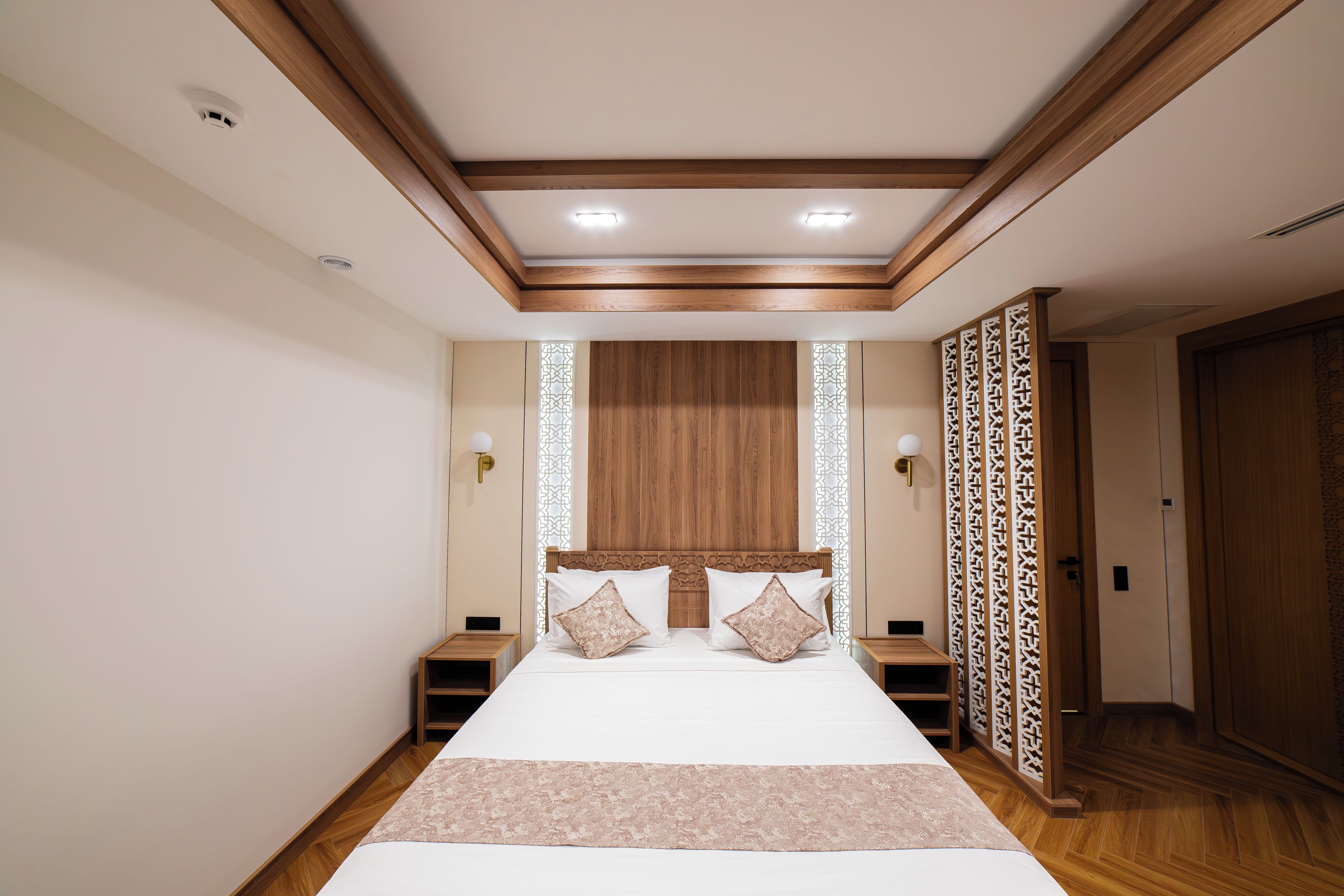 Una camera da letto con un letto grande, una testata in legno, comodini e un pannello decorativo.