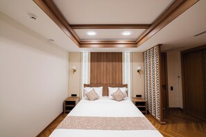 Un dormitorio con una cama grande, cabecera de madera, mesitas de noche y un separador decorativo.