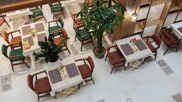 Un restaurante con varias mesas, sillas y una planta grande en maceta.