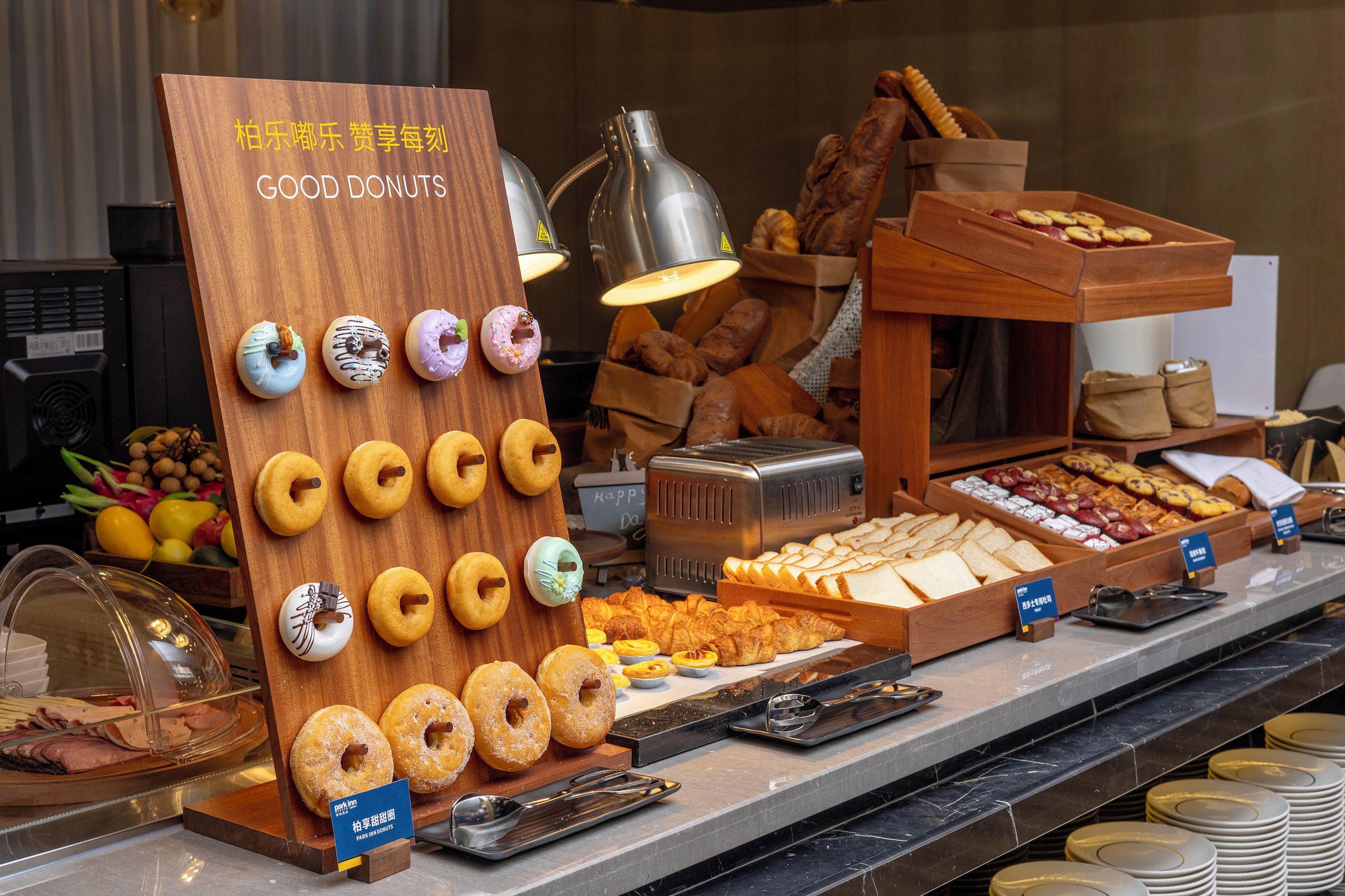A breakfast buffet with various pastries, including donuts, bread, and pastries, arranged on a counter.